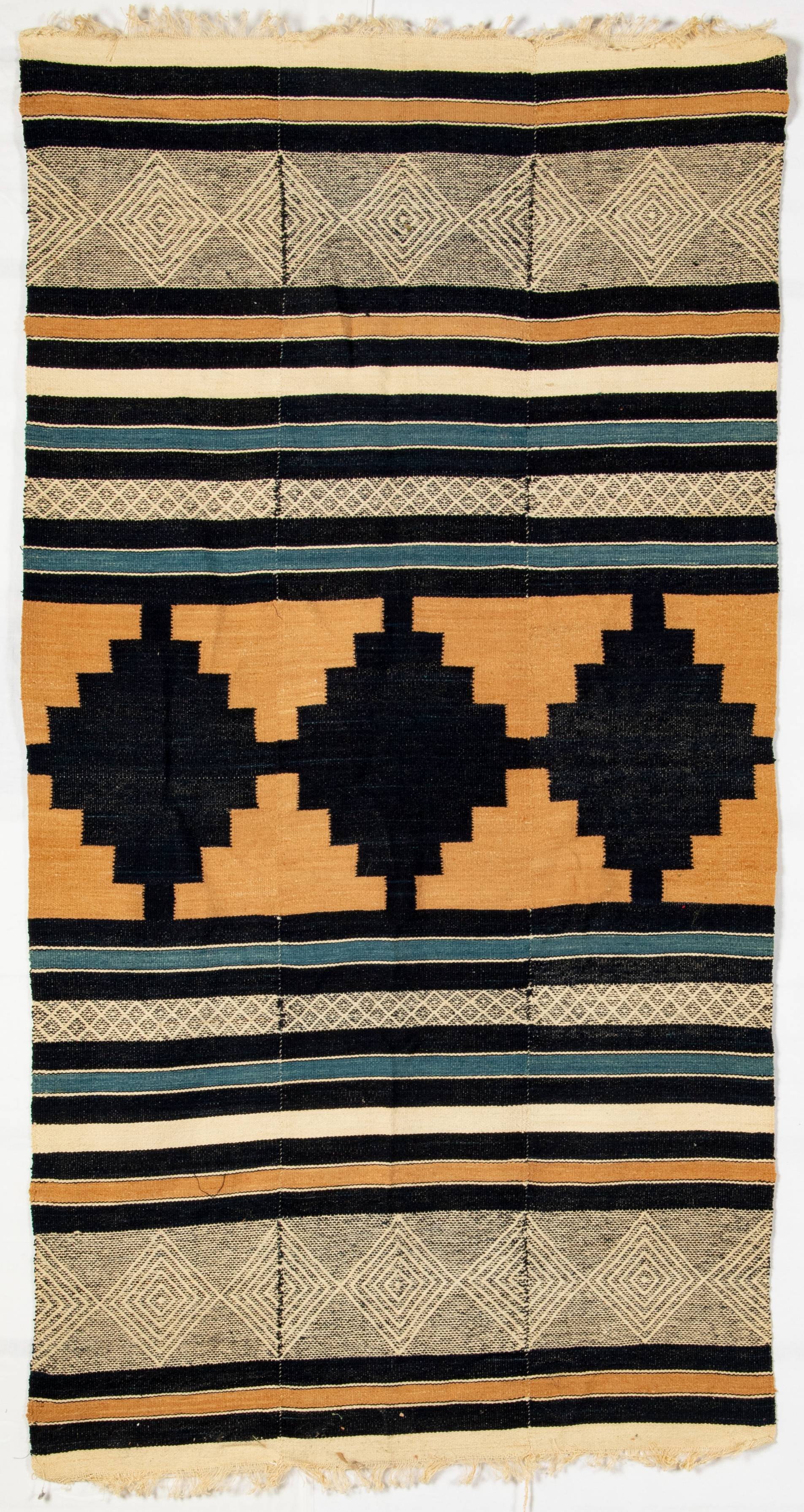 woven blanket with white, black, teal, and orange geometric patterns